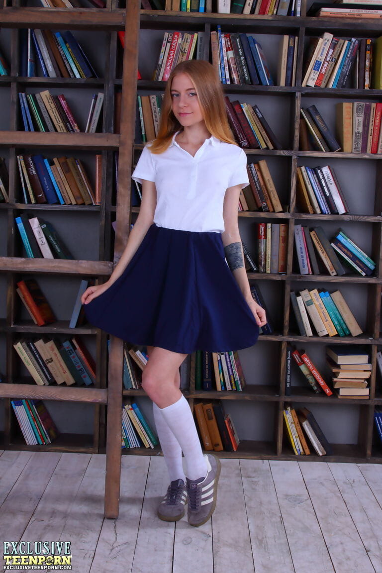 Slim schoolgirl Chloe strips to knee socks in front of book stack