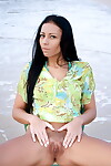 Slim dark haired beauty removes sheer panties to pose with chair at the beach