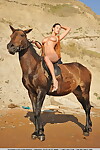 Big titted Suzanna A shows shaved twat posing naked on beach with horse