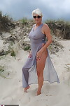 Beautiful busty mature Dimonty poses fully clothed in sheer dress at the beach