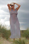 Beautiful busty mature Dimonty poses fully clothed in sheer dress at the beach