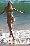 Blonde solo girl Chloe Toy wades into the surf wearing a thong bikini