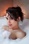 Busty amateur Katie Banks pets her shaved pussy while taking a bubble bath